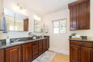 Ensuite primary bath with double vanity, granite countertops and cherry cabinets