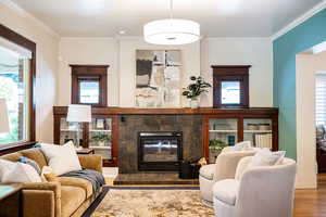 Living room featuring original glass-front built in cabinets, gas-log fireplace and a huge front window.