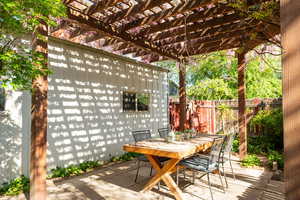 Outdoor entertaining space with wisteria covered pergola and candle-lit chandelier