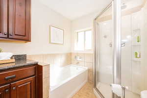 Ensuite primary bath with separate tub and shower, granite countertops and cherry cabinets