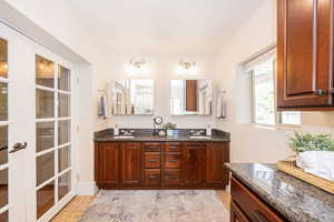 Ensuite primary bath with double vanity, granite countertops and cherry cabinets