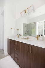 Bathroom with a sink, tile patterned floors, a stall shower, and double vanity