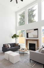 Living room featuring a high ceiling, a fireplace, ceiling fan, and visible vents