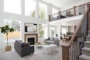 Living area with a towering ceiling, baseboards, stairway, and a high end fireplace