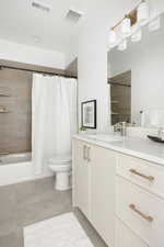 Bathroom featuring toilet, visible vents, shower / bathtub combination with curtain, and vanity