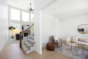 Living area with baseboards, ceiling fan, wood finished floors, and stairway