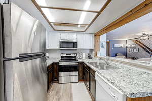 Kitchen with light countertops, appliances with stainless steel finishes, white cabinetry, and a sink