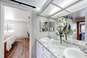 Ensuite bathroom with a baseboard radiator, wood finished floors, a sink, a textured ceiling, and connected bathroom