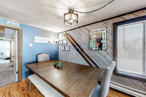 Dining area with a wealth of natural light, a textured ceiling, a notable chandelier, wood finished floors, and wooden walls