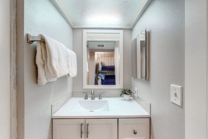 Bathroom with a textured wall, vanity, and visible vents