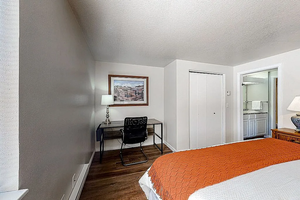 Bedroom featuring a textured ceiling, wood finished floors, ensuite bathroom, a closet, and baseboards