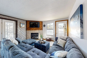 Living area featuring a tiled fireplace, a textured ceiling, and a healthy amount of sunlight