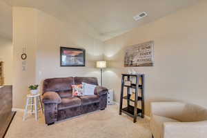 Carpeted sitting room with vaulted ceilings