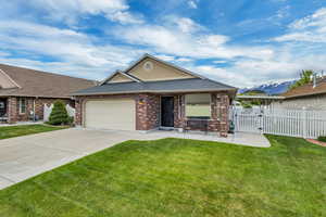 Patio home featuring fence, an attached garage, concrete driveway, and a front yard