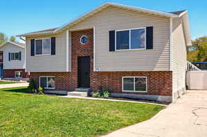 Bi-level home featuring brick siding, a front lawn, and driveway