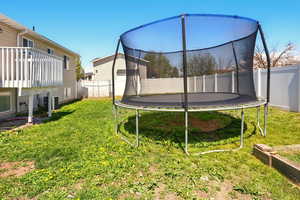 View of yard with a fenced backyard, a trampoline, and central air condition unit