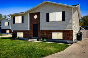 Split foyer home featuring brick siding and a front yard