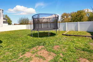 View of yard with a fenced backyard and a trampoline