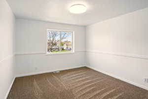Carpeted spare room with visible vents and baseboards