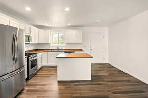 Kitchen featuring a sink, appliances with stainless steel finishes, wooden counters, and recessed lighting