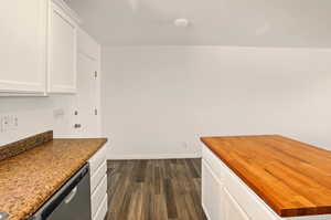 Kitchen featuring dark wood-style flooring, butcher block countertops, white cabinetry, and dishwasher