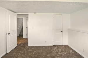 Spare room featuring baseboards, a textured ceiling, and carpet