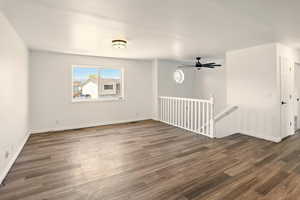Spare room featuring baseboards, ceiling fan, and dark wood-style floors