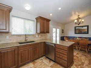 Kitchen with a sink, stainless steel appliances, a peninsula, lofted ceiling, and tasteful backsplash