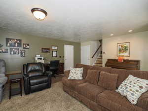 Carpeted living room with recessed lighting, a textured ceiling, and stairway