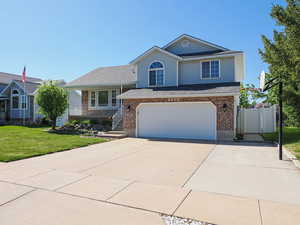 Split level home with brick siding, an attached garage, driveway, and a front yard