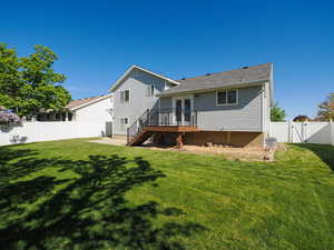 Rear view of house featuring a wooden deck, a gate, stairway, a fenced backyard, and a yard
