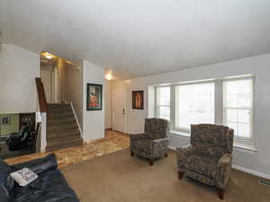 Carpeted living room featuring visible vents, baseboards, vaulted ceiling, and stairway