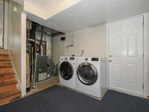 Laundry room featuring washer and dryer, a textured ceiling, laundry area, and heating unit