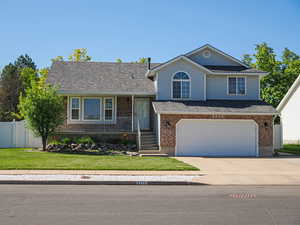 View of front of home featuring a garage, a front lawn, fence, concrete driveway, and a porch