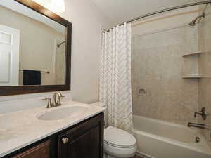 Bathroom with toilet, shower / tub combo, and vanity