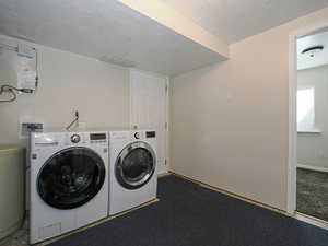Laundry room with a textured ceiling, laundry area, and independent washer and dryer