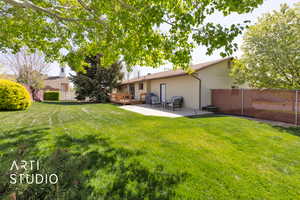 Back of property featuring a yard, a deck, fence, and a patio
