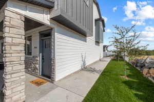 Property entrance with a lawn, board and batten siding, and stone siding