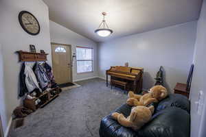 Carpeted living area featuring baseboards, vaulted ceiling, and visible vents