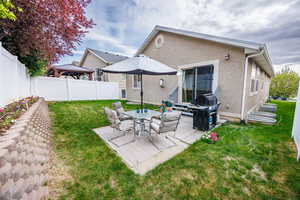 Rear view of house with a gazebo, a fenced backyard, a lawn, and stucco siding
