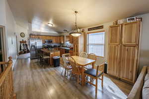 Dining room with light wood-style floors and vaulted ceiling
