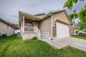 View of front facade with a garage, a front yard, stucco siding, concrete driveway, and central air condition unit
