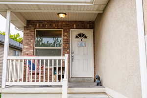 View of exterior entry featuring stucco siding and covered porch