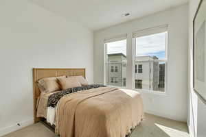 Bedroom with light colored carpet, baseboards, and visible vents