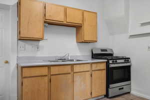 Kitchen with light countertops, light tile patterned floors, stainless steel gas stove, and a sink