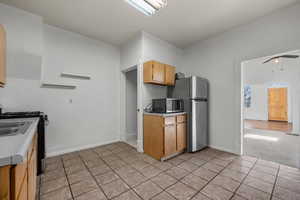 Kitchen with ceiling fan, light tile patterned floors, light countertops, baseboards, and stainless steel appliances