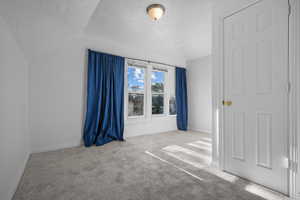 Interior space with carpet floors, baseboards, and lofted ceiling