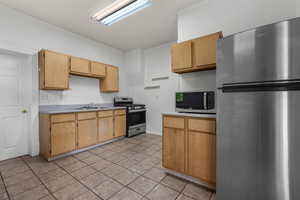 Kitchen with light countertops, a sink, appliances with stainless steel finishes, and light tile patterned floors