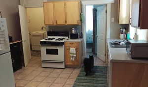 Kitchen featuring light countertops, light tile patterned floors, white appliances, and washer / clothes dryer