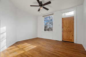 Foyer featuring baseboards, a ceiling fan, wood finished floors, and visible vents